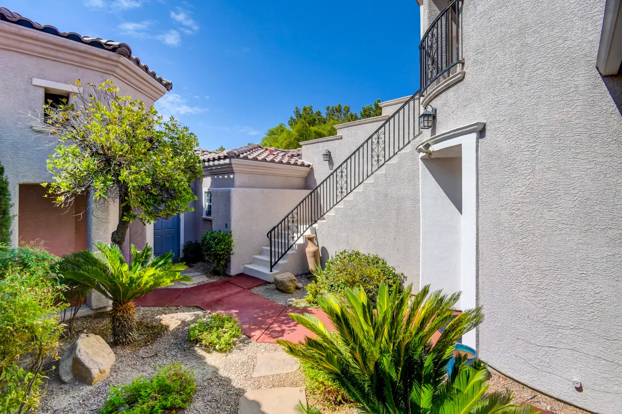 Private courtyard with palms and an exterior stair rising to the upstairs room