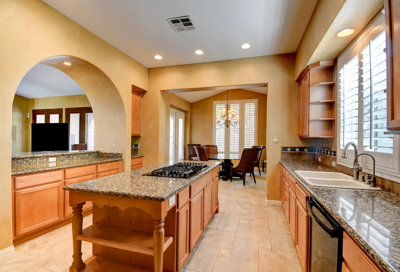 Kitchen seen through an arched pass with the island and built-in shelving