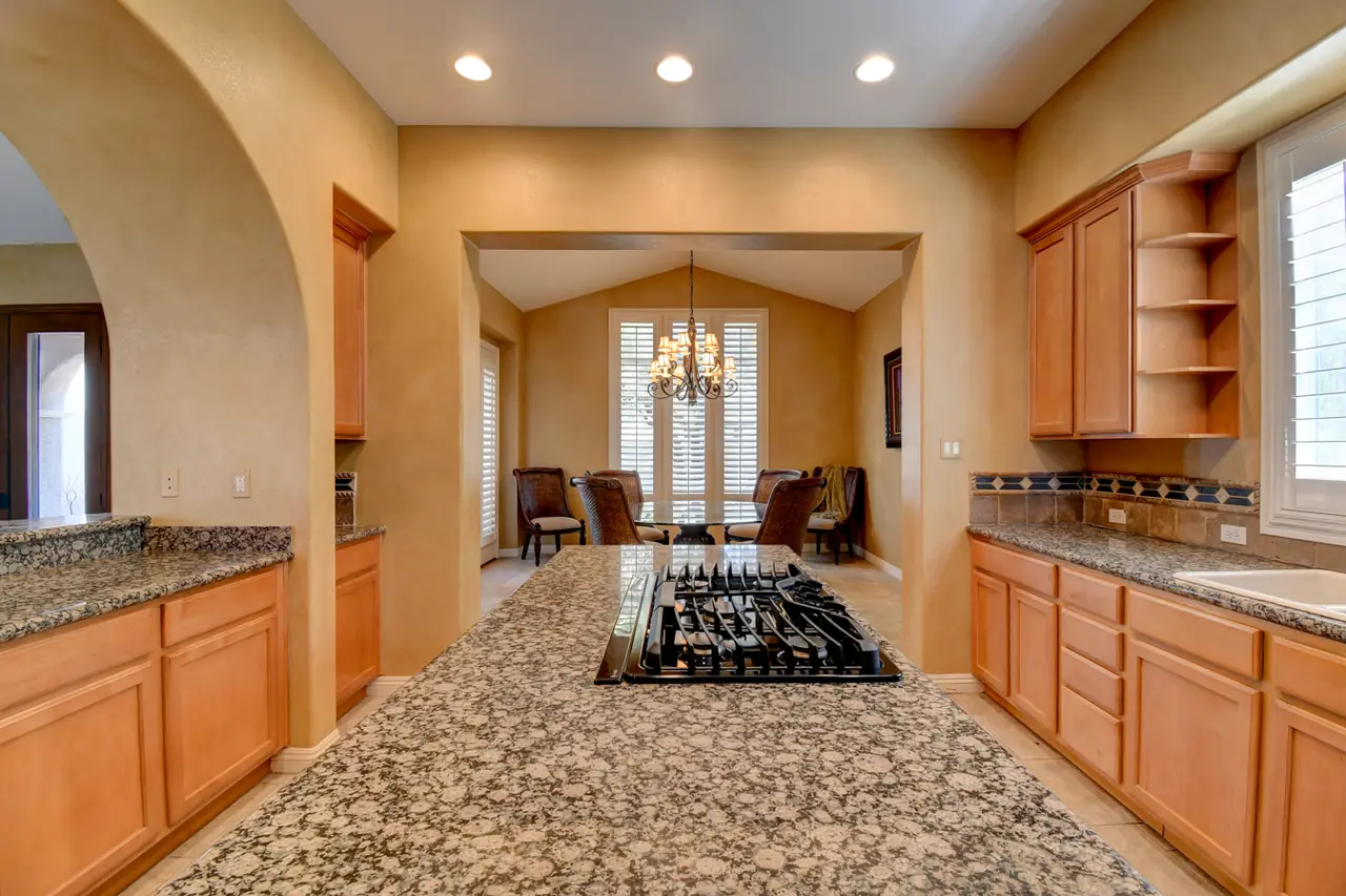 Granite kitchen island with gas cooktop facing the breakfast area