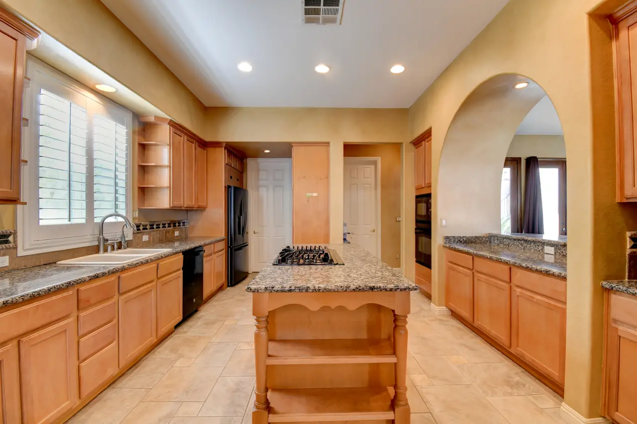Kitchen with wood cabinetry, granite counters and arched opening to the living area