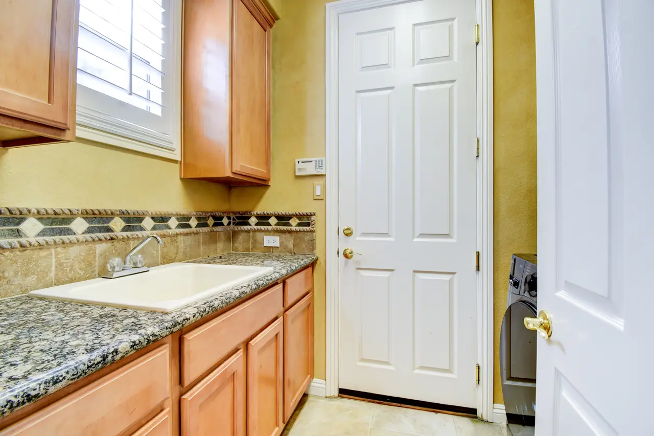 Laundry room with granite counter, sink and wood cabinets