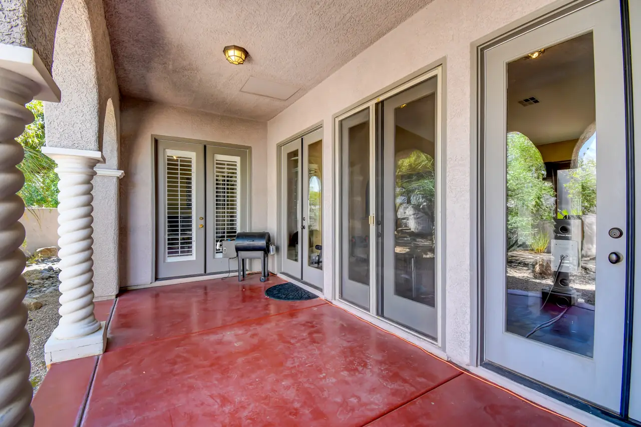 Covered loggia with red stained concrete and multiple French doors