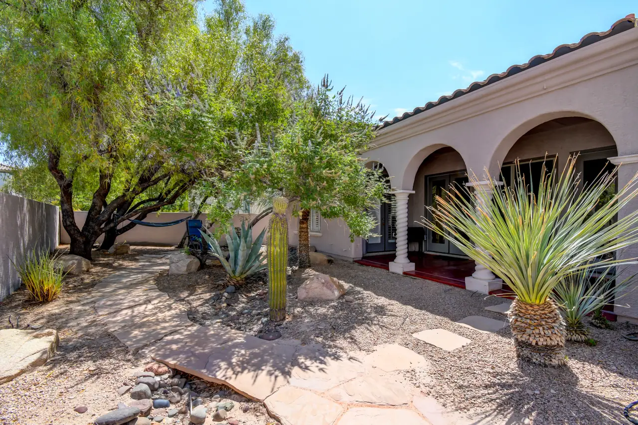 Arched loggia overlooking a desert garden with yucca and mature trees