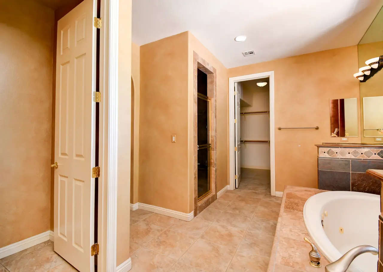 Primary bath tub and walk-in closet doorway