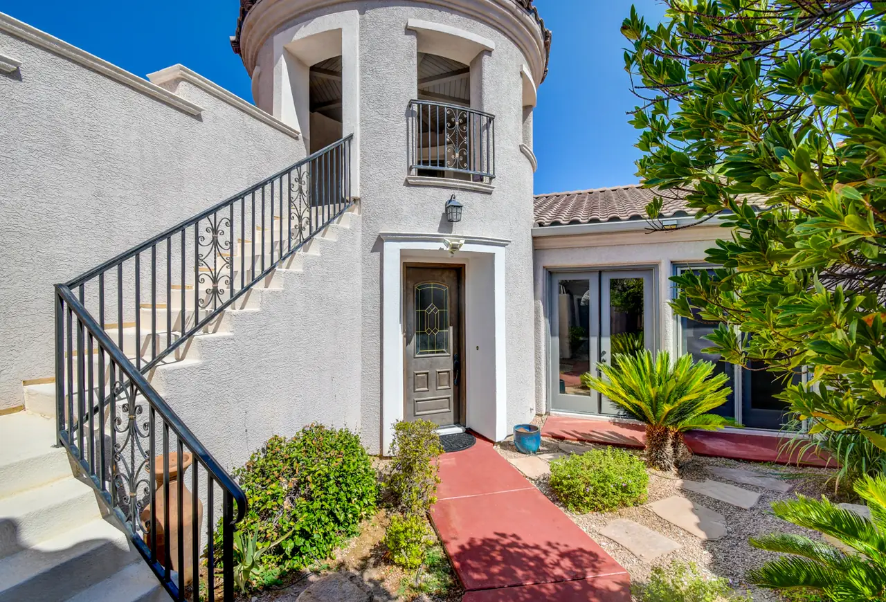 Stucco tower with an iron-railed exterior staircase, balcony and front door