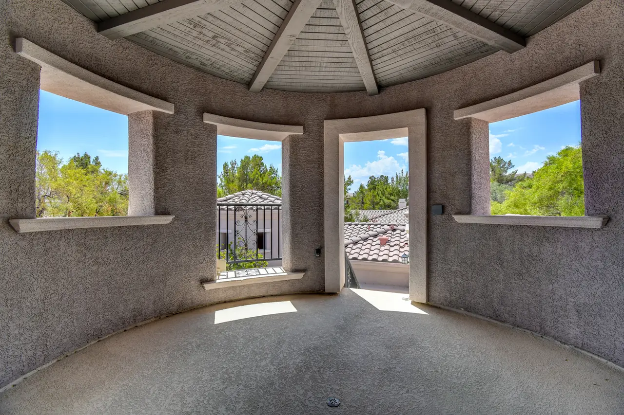 Octagonal tower room with open windows over treetops and tile roofs